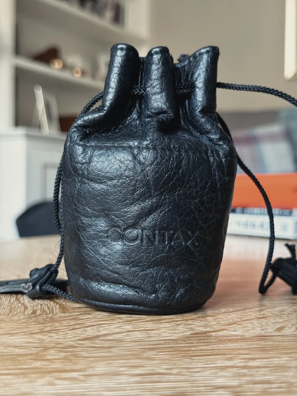 A black leather drawstring lens pouch embossed with the Contax logo