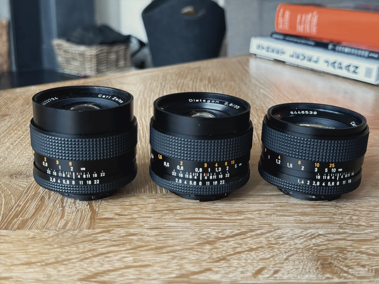 Three Zeiss lenses side by side on a table: the Distagon 28mm f2.8, Distagon 35mm f2.8 and Planar 50mm f1.4