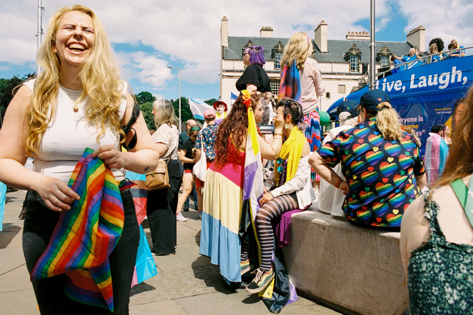 A laughing woman holding a rainbow flag in a crowd at a Pride event