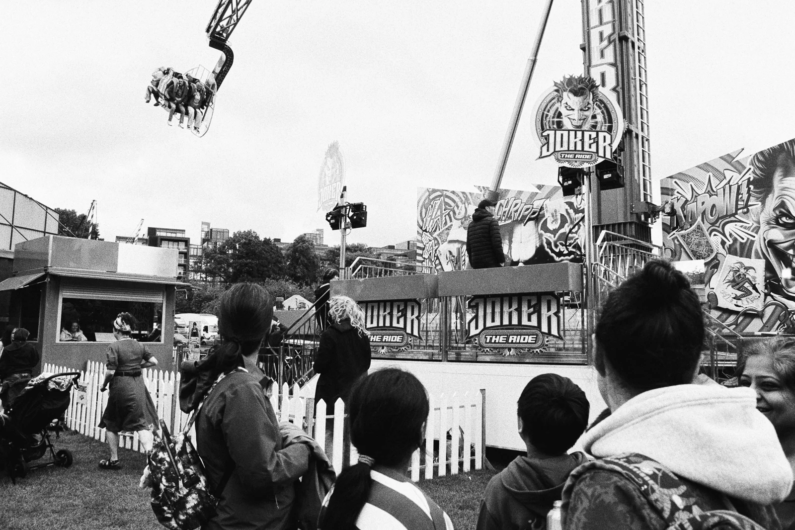 A crowd watching a fairground ride swing riders high into the air