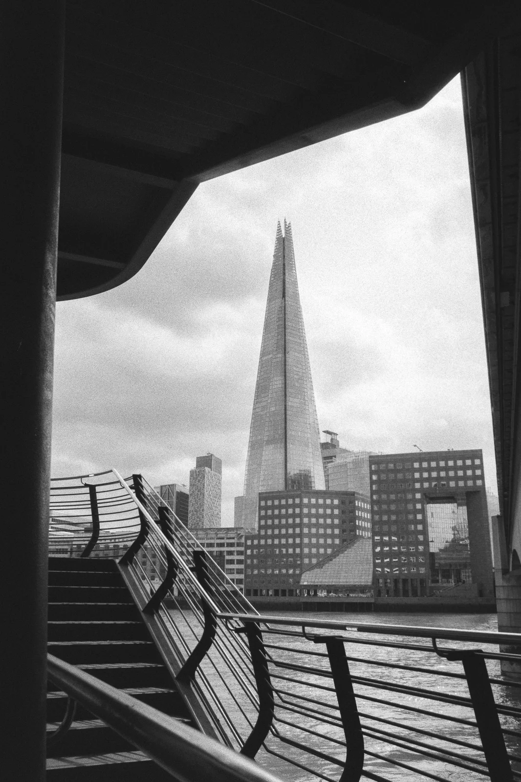 The Shard framed by a dark underpass and curving riverside railings