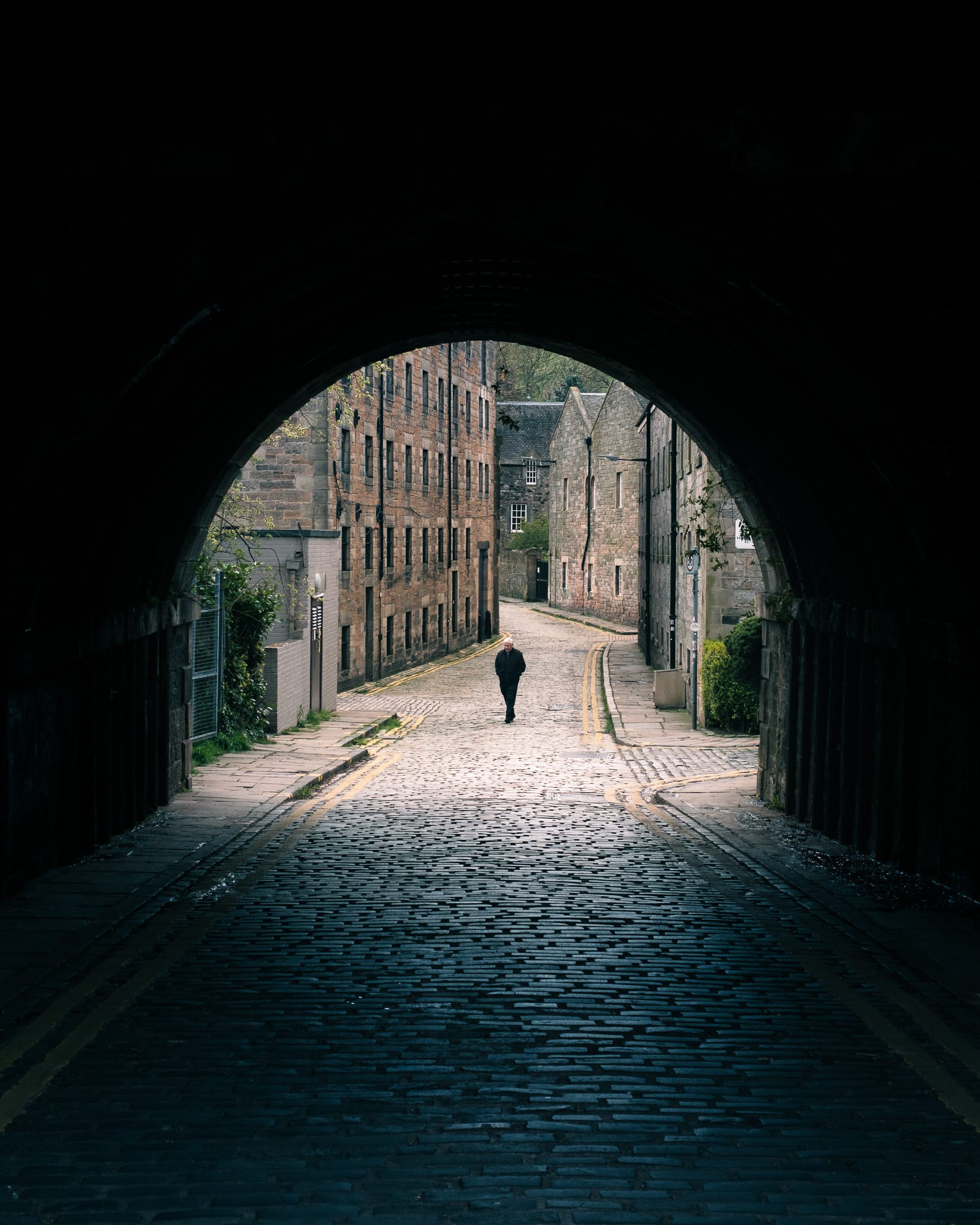 A man walks alone under a bridge