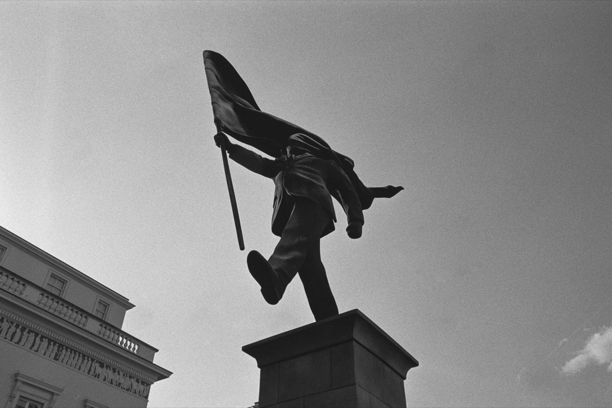 Statue carrying a flag against the sky